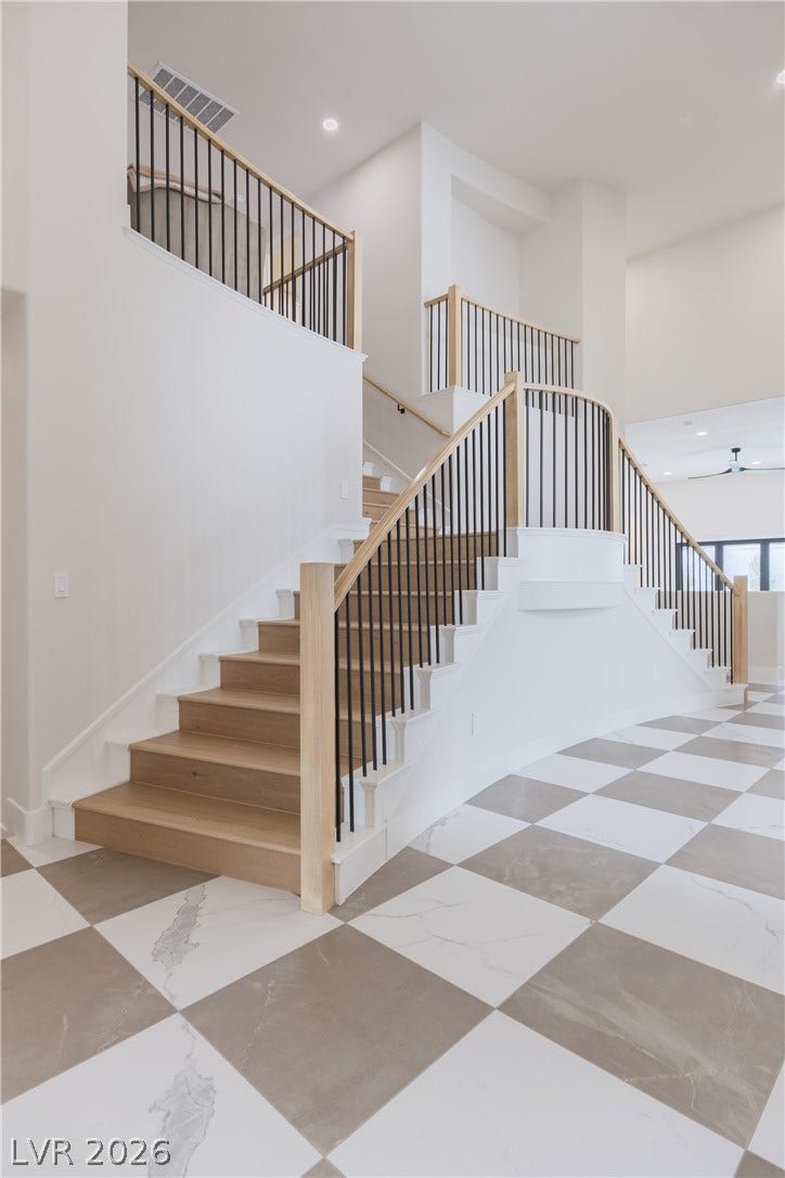 Stairway featuring a high ceiling, ceiling fan, and recessed lighting