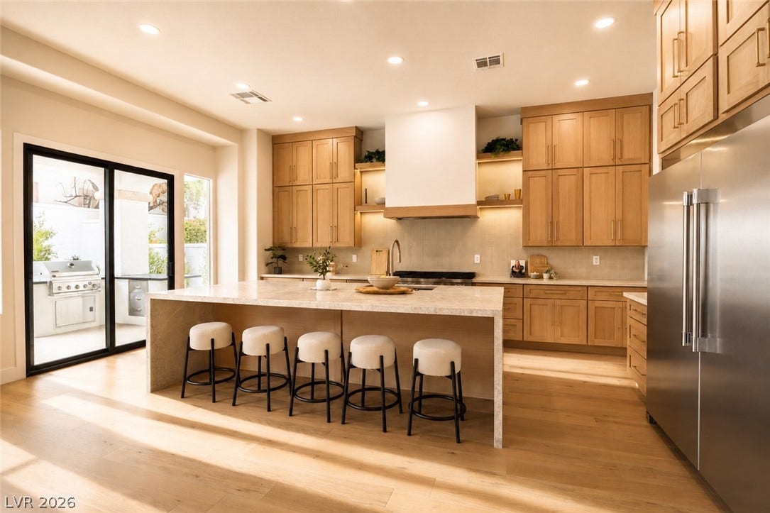 Sun-kissed hardwood floors lead to a grand kitchen island, perfect for casual dining and entertaining.