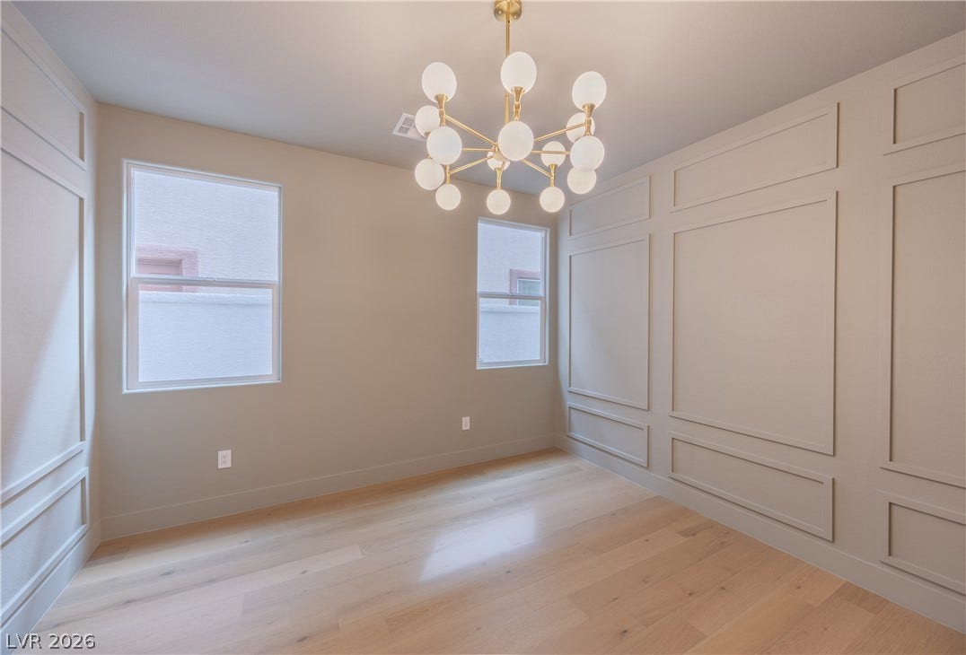 Unfurnished dining area featuring hanging lights, light wood finished floors, and a decorative wall