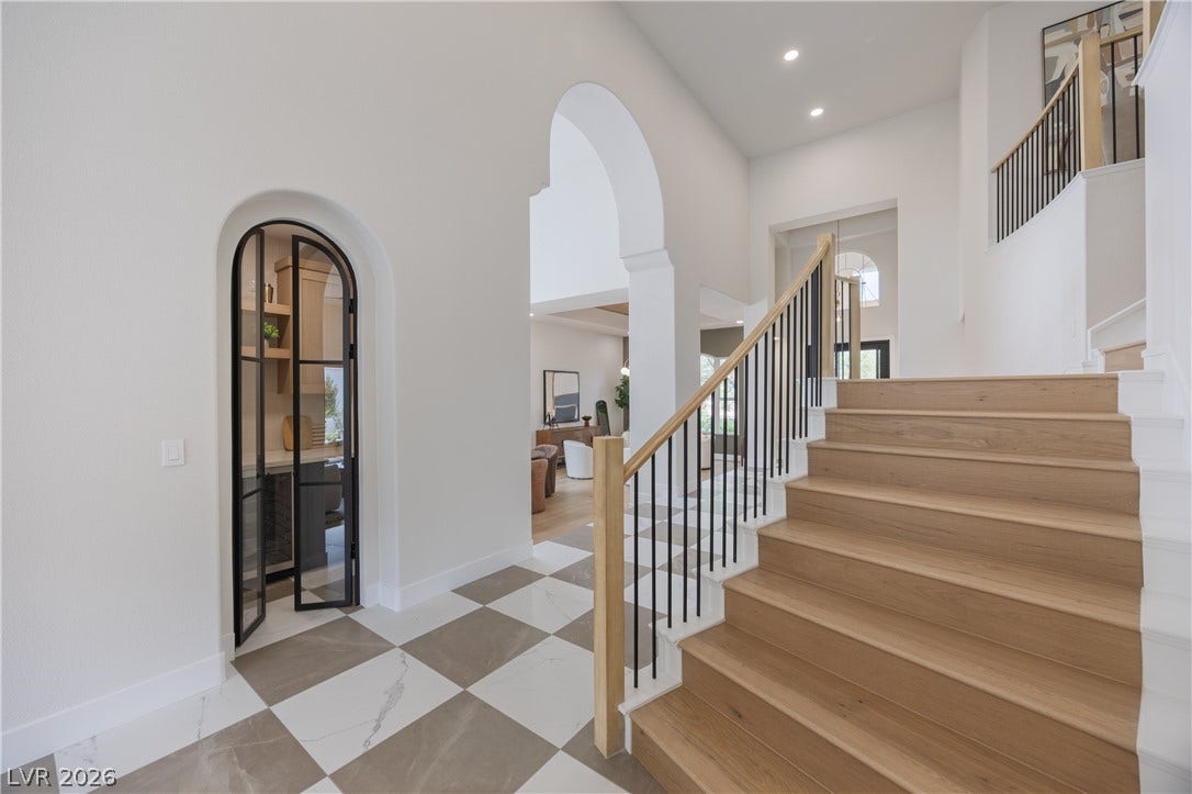 Stairway with recessed lighting, arched walkways, and a high ceiling