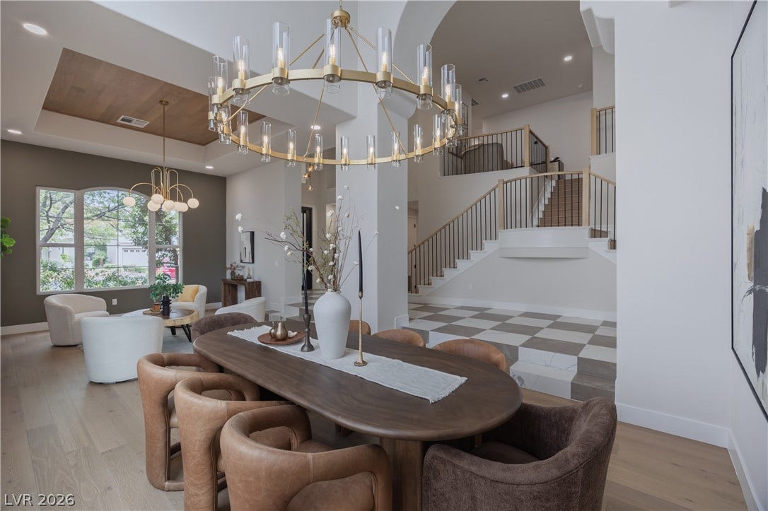 Dining room with suspended lighting, light wood-type flooring, and a tray ceiling
