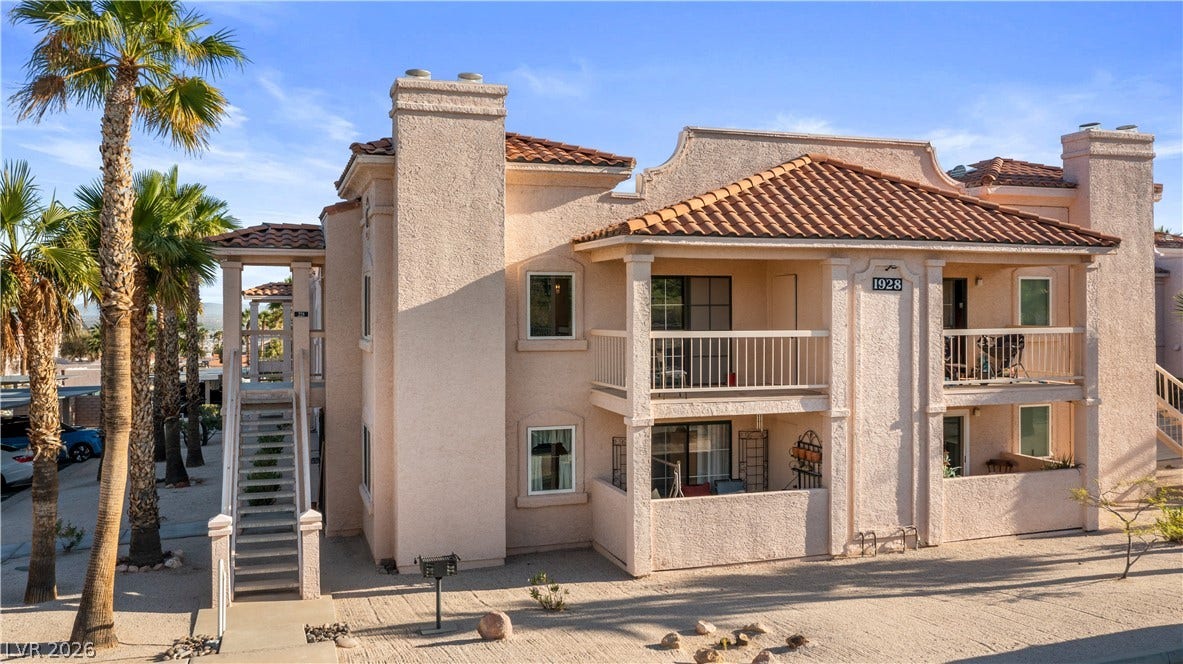 Back of house with stucco siding, a tiled roof, a balcony, and a chimney