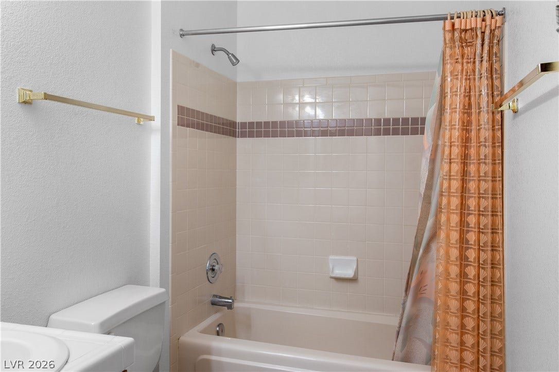 Hall Bathroom featuring shower / bath combo, a textured wall, and toilet