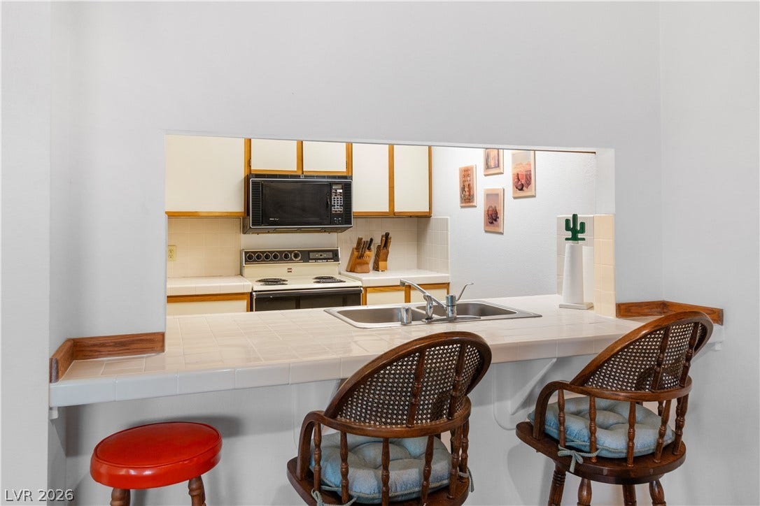 Kitchen featuring black microwave, white electric stove, a sink, and tile countertops