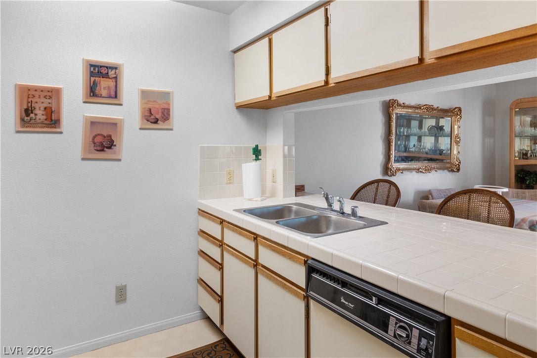 Kitchen featuring white dishwasher, a sink, tasteful backsplash, a peninsula, and baseboards
