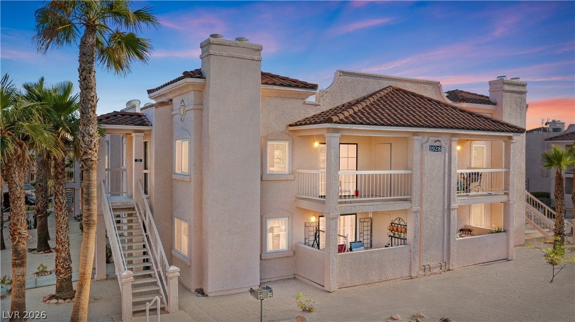 Front of property at dusk with a balcony, a tile roof, stucco siding, stairs, and a chimney