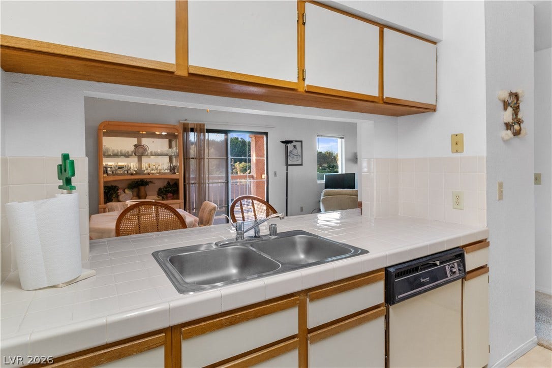 Kitchen featuring dishwasher, a sink, light countertops, and white cabinetry