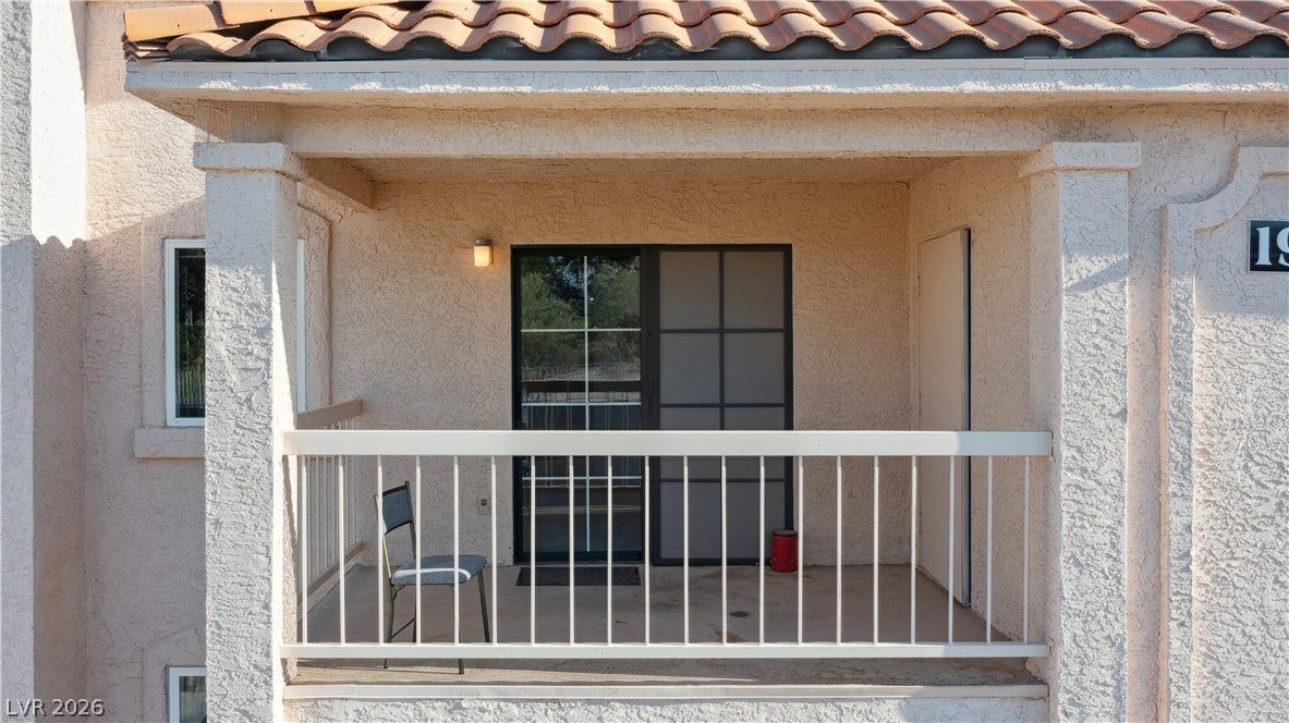 Covered balcony with access to Living room / Dining area featuring a tile roof and stucco siding