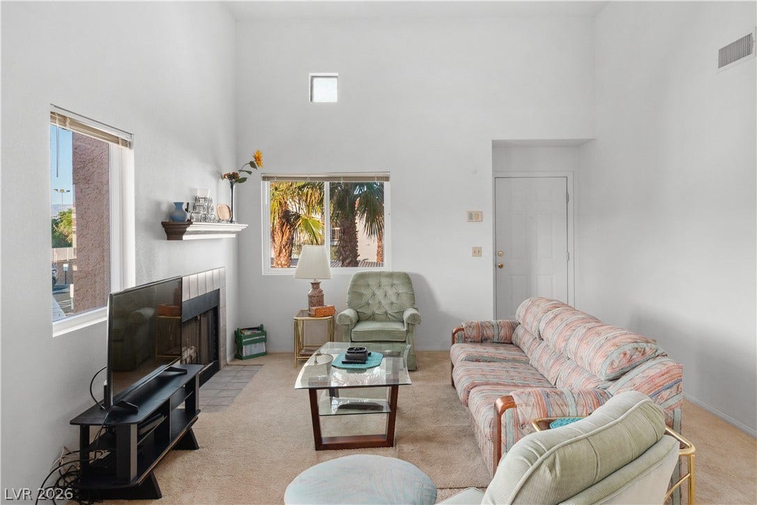 Carpeted living room featuring a towering ceiling and a tile fireplace