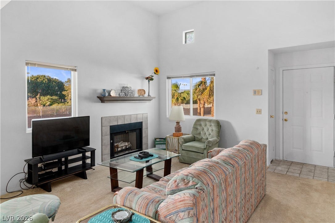 Carpeted living area with a towering ceiling, a tile fireplace, and tile patterned flooring