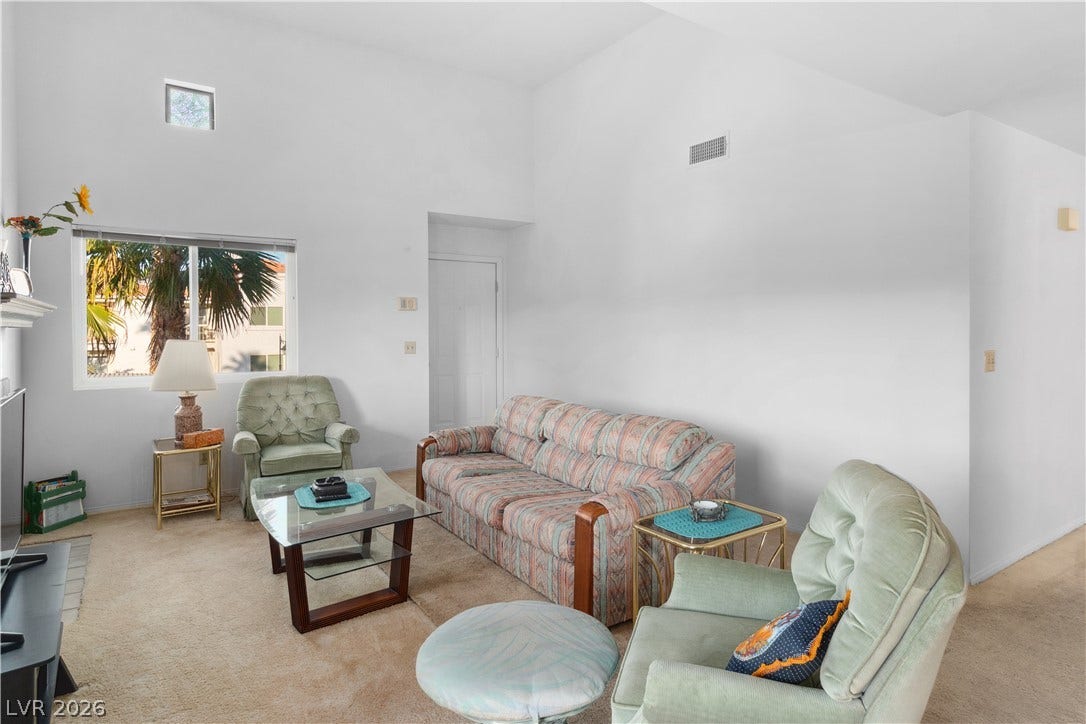 Living area with a high ceiling, carpet floors, and plenty of natural light