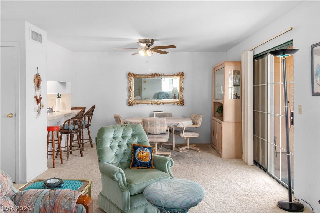 Carpeted living area with a ceiling fan