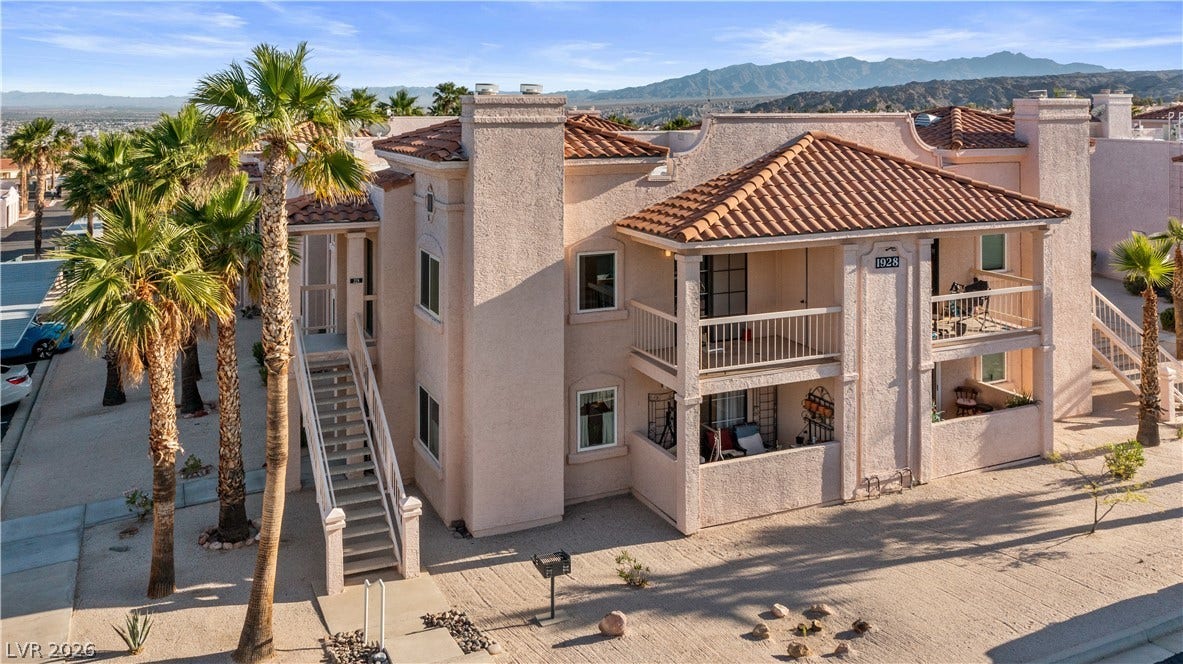 View of front of house with a chimney, a balcony, stucco siding, and a tiled roof