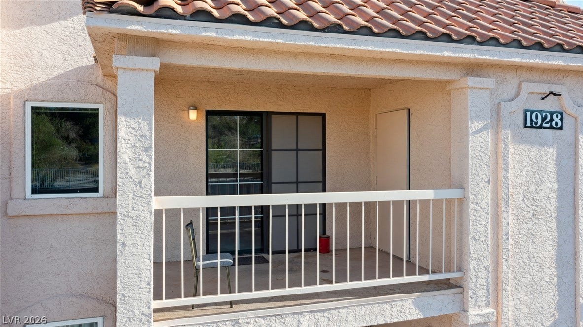View of covered balcony with access to Living room and Dining area featuring stucco siding and a tile roof