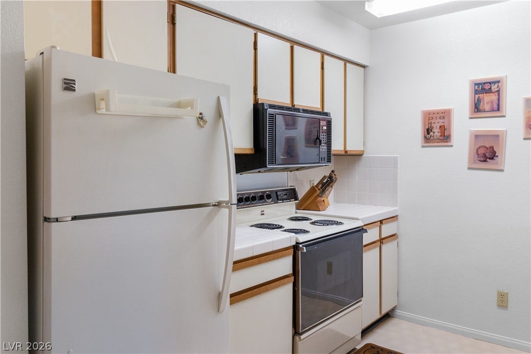 Kitchen featuring white appliances, backsplash, and tile counters