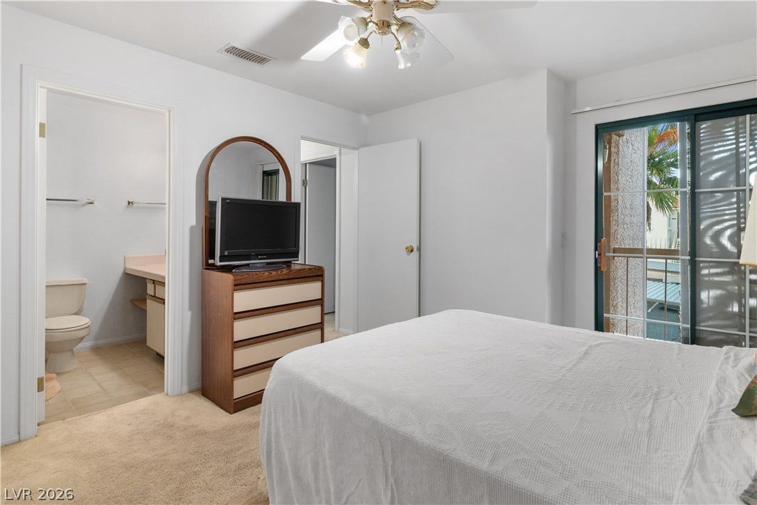 Primary Bedroom featuring light carpet, ensuite bathroom, a ceiling fan, and baseboards