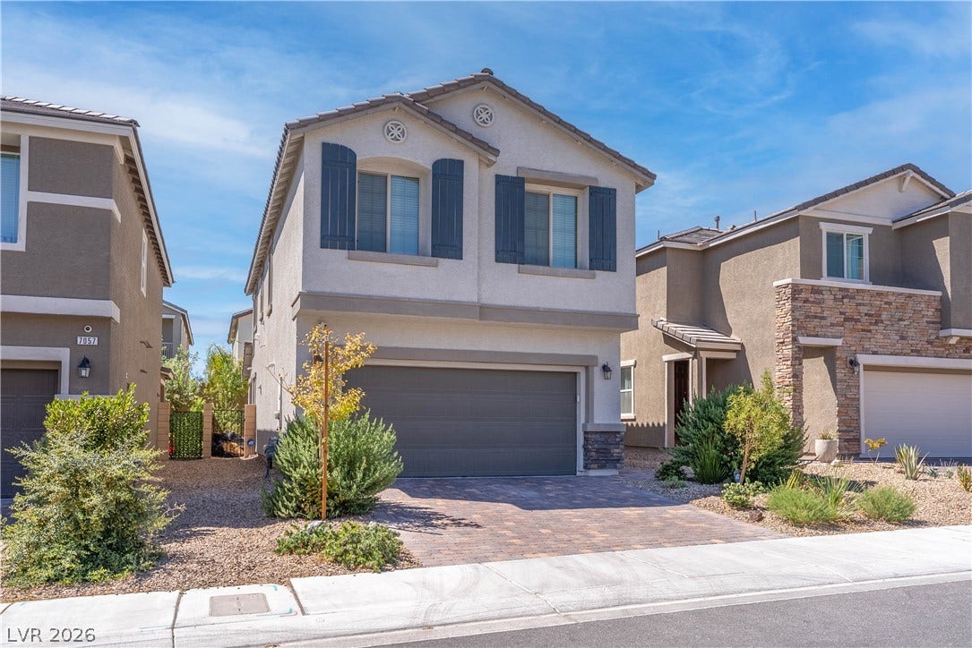 7061 Tilligerry Street, North Las Vegas, NV 89084 A classic two-story exterior showcases detailed stonework, window shutters, and a paved driveway.
