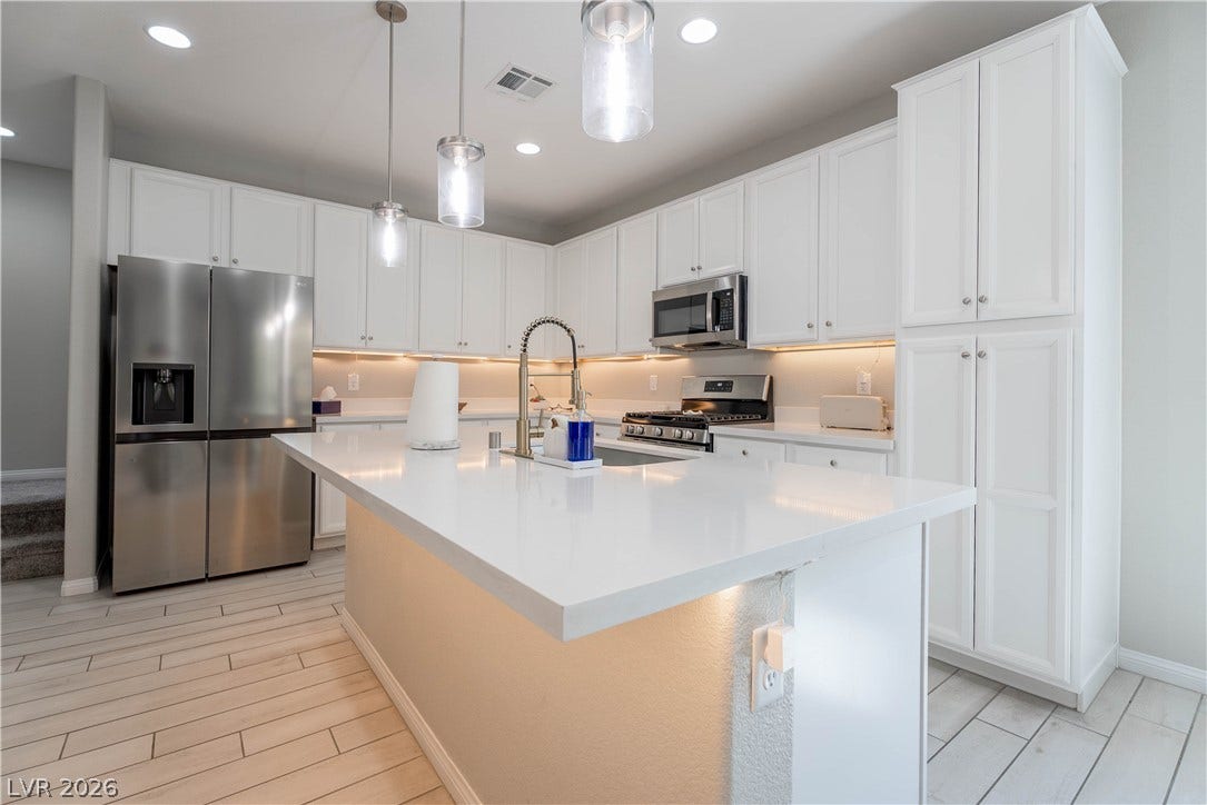 7061 Tilligerry Street, North Las Vegas, NV 89084 Gleaming quartz countertops and matching cabinetry surround a central prep island with built-in storage.