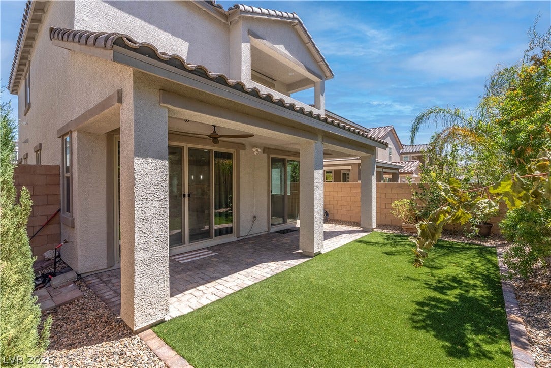 7061 Tilligerry Street, North Las Vegas, NV 89084 A covered brick patio opens to a manicured grassy yard enclosed by a block fence.
