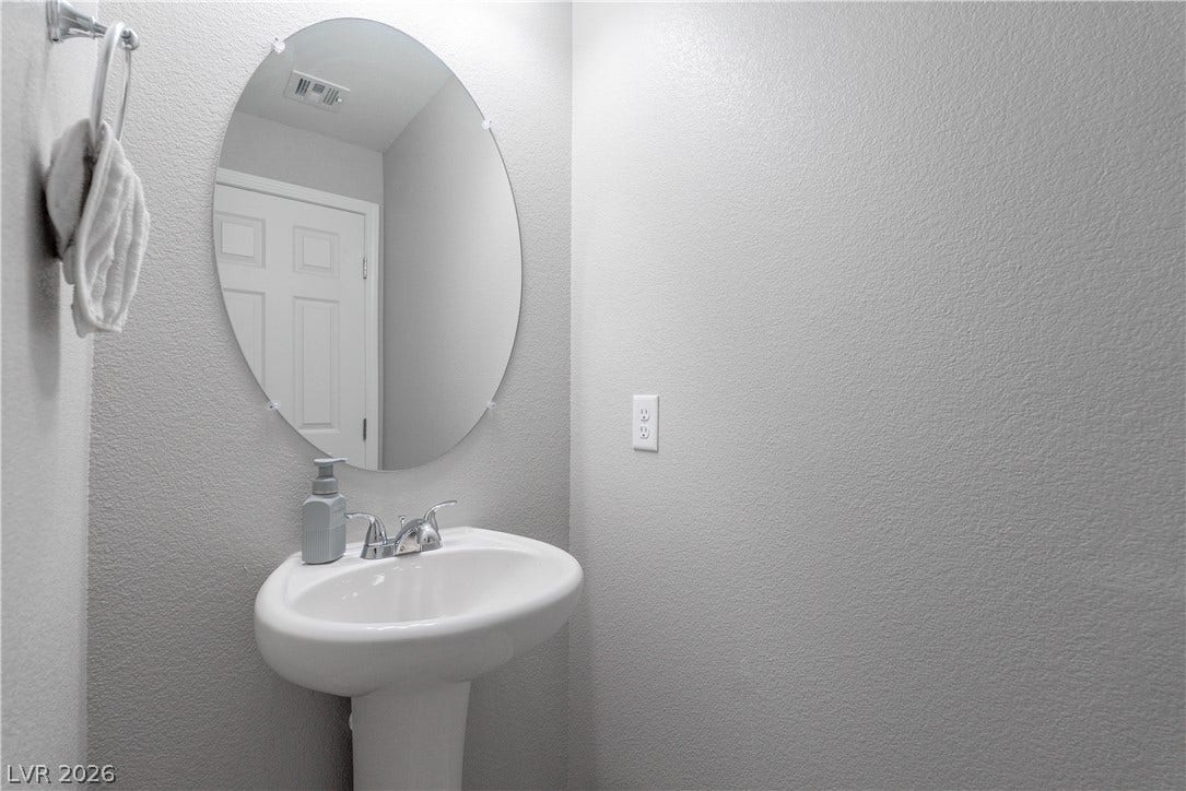 7061 Tilligerry Street, North Las Vegas, NV 89084 A classic pedestal sink and oval mirror anchor this neat powder room.