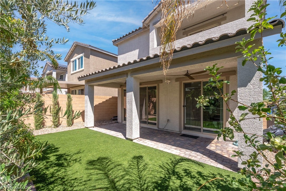7061 Tilligerry Street, North Las Vegas, NV 89084 A covered brick paver patio extends from the home toward a manicured green lawn.