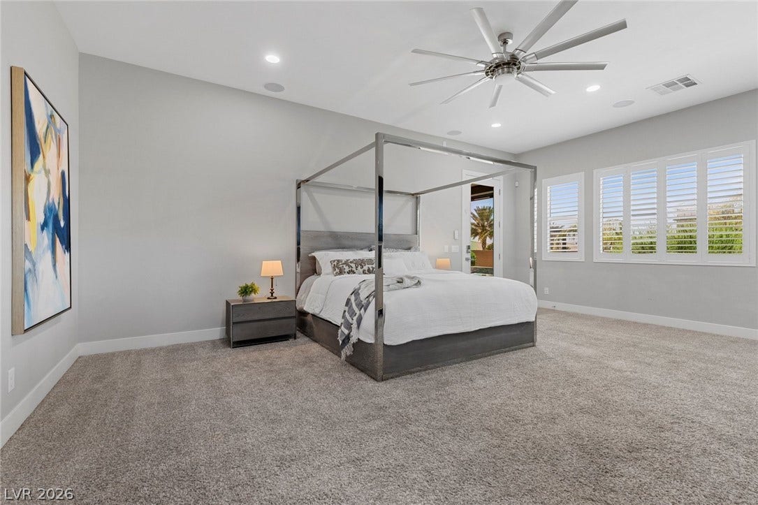 9841 W El Campo Grande Avenue, Las Vegas, NV 89149 Luxurious primary suite with plush carpeting and expansive windows invites relaxation and outdoor access.