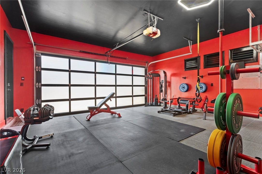 9841 W El Campo Grande Avenue, Las Vegas, NV 89149 A well-appointed home gym featuring robust exercise equipment and a translucent garage door.