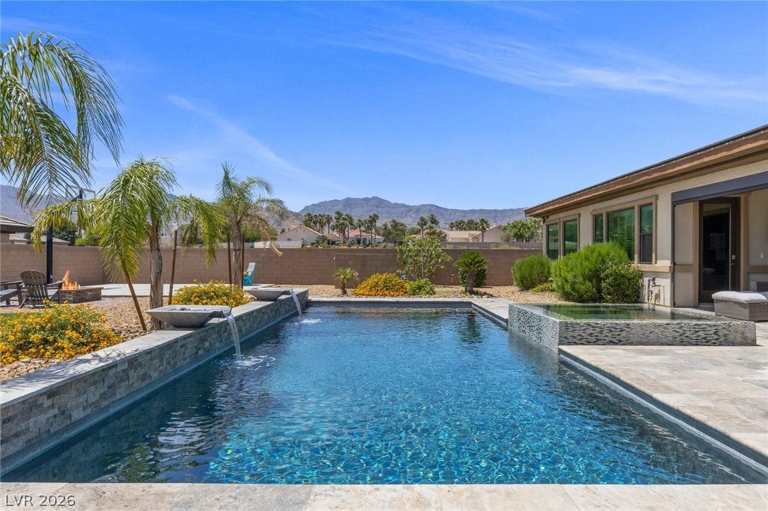 9841 W El Campo Grande Avenue, Las Vegas, NV 89149 Lush landscaping and serene water features frame a sparkling pool and spa with mountain views.
