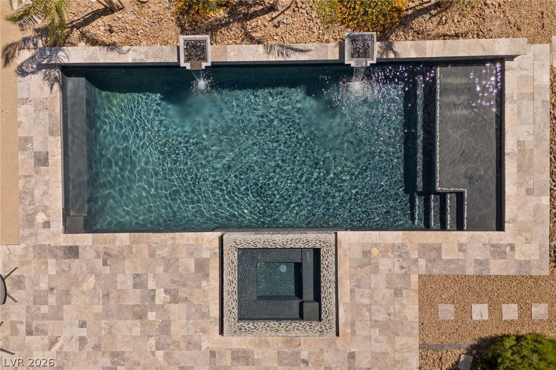 9841 W El Campo Grande Avenue, Las Vegas, NV 89149 An inviting backyard oasis features a glistening pool and integrated spa, surrounded by attractive tile paving.