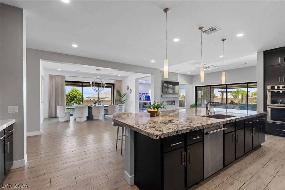 9841 W El Campo Grande Avenue, Las Vegas, NV 89149 An open concept kitchen features a large island with granite countertops, seamlessly connecting to a spacious dining area and living space.