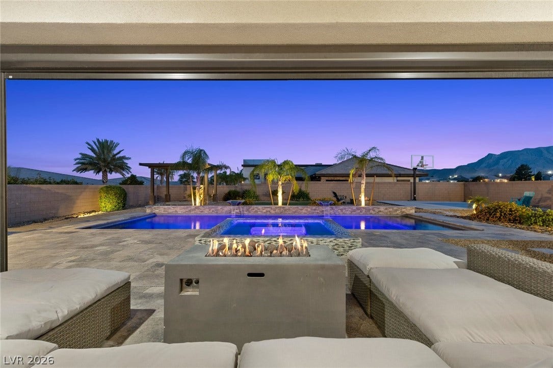 9841 W El Campo Grande Avenue, Las Vegas, NV 89149 An inviting outdoor space features a private pool and a cozy fire pit against a twilight mountain backdrop.