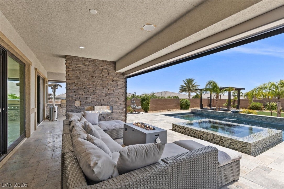 9841 W El Campo Grande Avenue, Las Vegas, NV 89149 An inviting outdoor living area seamlessly connects to a refreshing pool and spa under a clear sky.