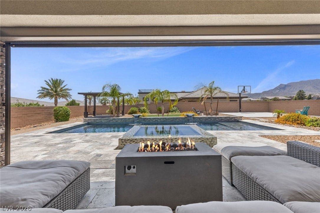 9841 W El Campo Grande Avenue, Las Vegas, NV 89149 An inviting backyard oasis with a shimmering pool, spa, and fire pit perfect for relaxation.