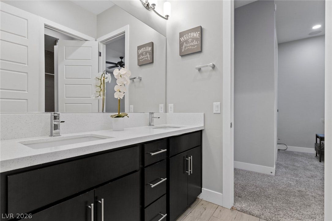 9841 W El Campo Grande Avenue, Las Vegas, NV 89149 Modern double vanity with pristine countertops and sleek dark cabinetry offers refined bathroom utility.