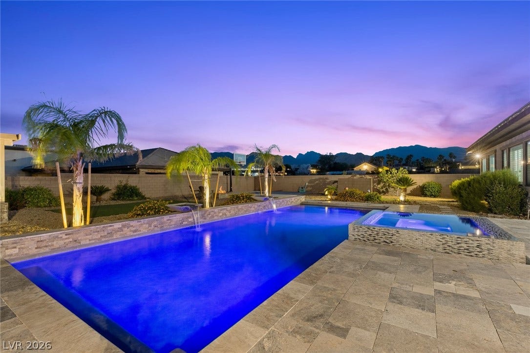 9841 W El Campo Grande Avenue, Las Vegas, NV 89149 An illuminated backyard oasis boasts a sparkling pool and spa with mountain views at twilight.