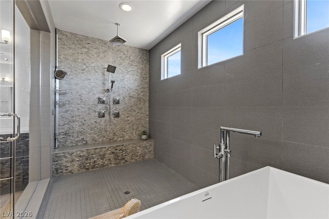 9841 W El Campo Grande Avenue, Las Vegas, NV 89149 Luxurious bathing experience in this contemporary bathroom with sleek tiling and abundant natural light.