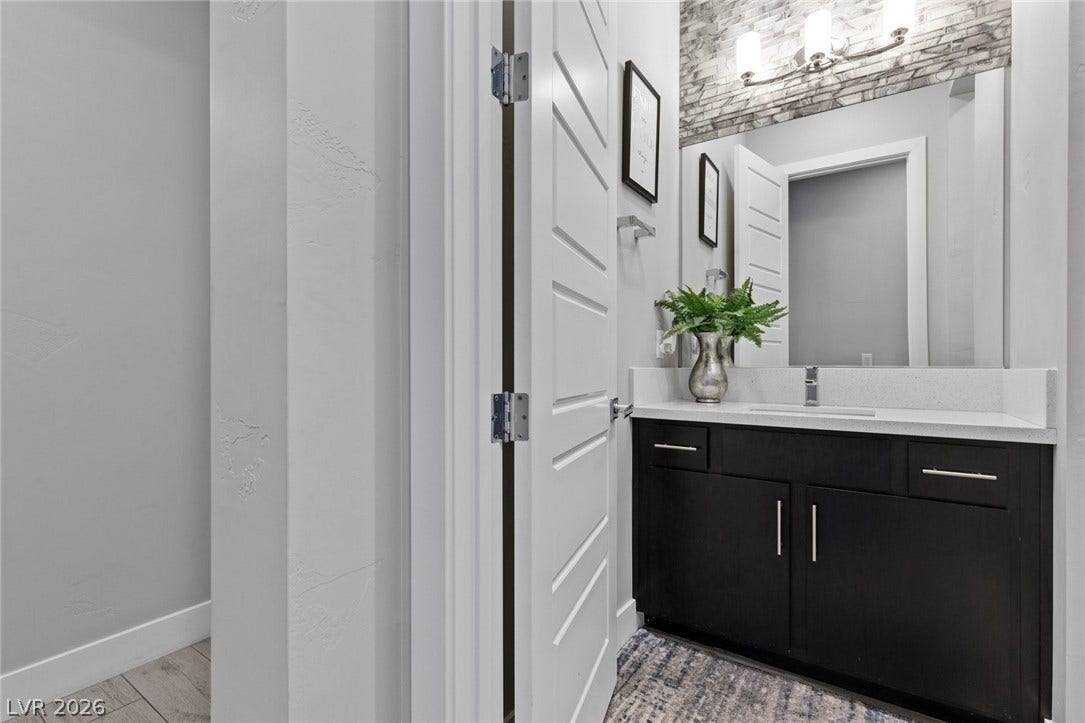 9841 W El Campo Grande Avenue, Las Vegas, NV 89149 Modern vanity with a large mirror and sleek fixtures enhances this refined bathroom space.