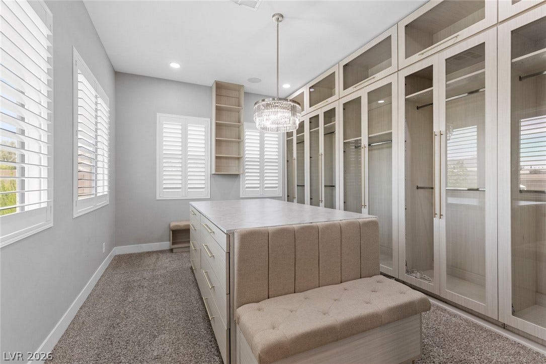 9841 W El Campo Grande Avenue, Las Vegas, NV 89149 Custom cabinetry and a central island define this well-appointed dressing room, complete with ample natural light.
