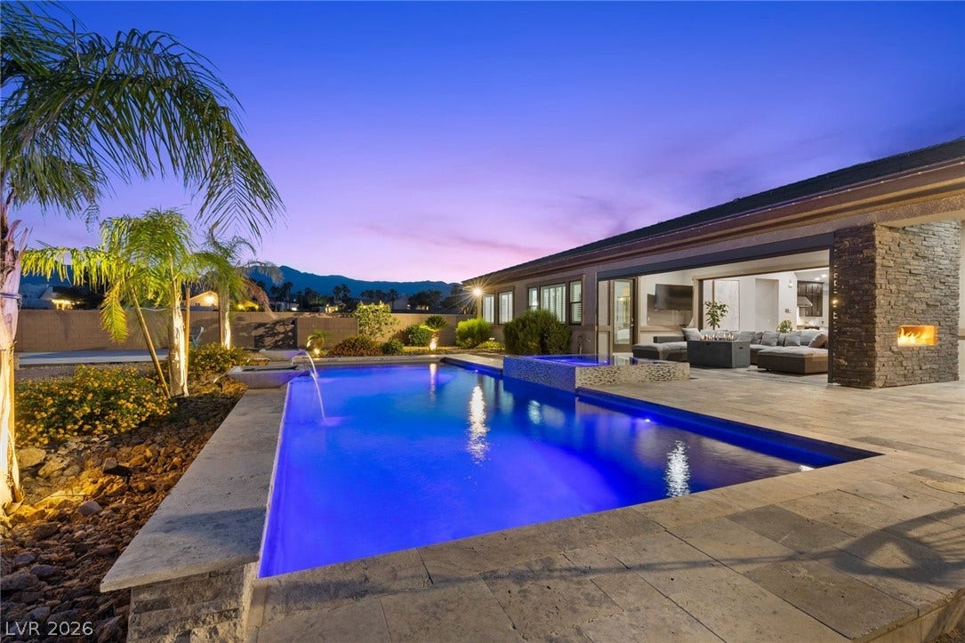 9841 W El Campo Grande Avenue, Las Vegas, NV 89149 An inviting backyard oasis features a shimmering pool, spa, and cozy outdoor fireplace, perfect for evening relaxation.