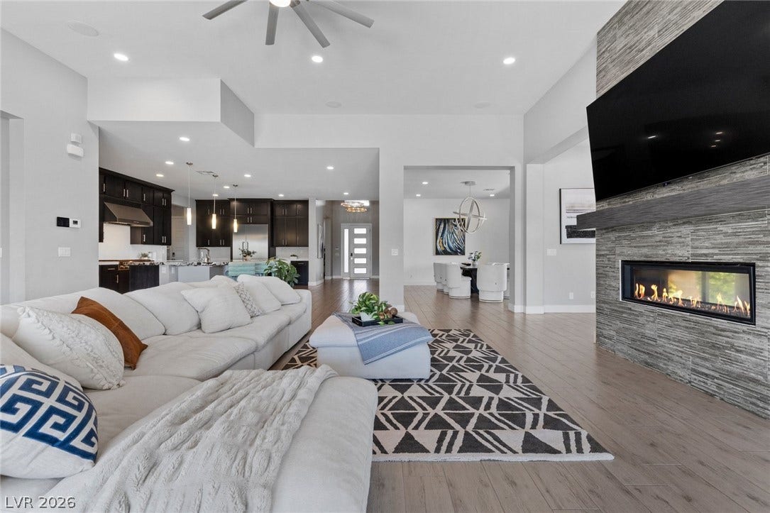 9841 W El Campo Grande Avenue, Las Vegas, NV 89149 An inviting open-concept living area flows seamlessly into the kitchen and dining space, highlighted by a contemporary fireplace.