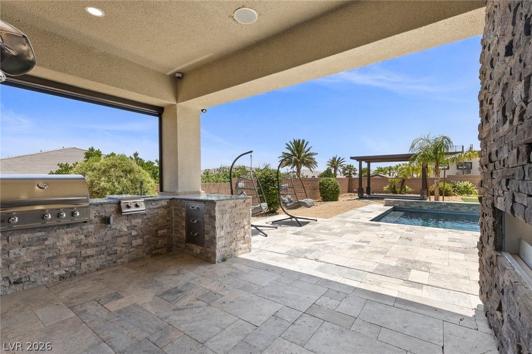 9841 W El Campo Grande Avenue, Las Vegas, NV 89149 An inviting outdoor kitchen seamlessly blends with a serene poolside oasis, perfect for entertaining.