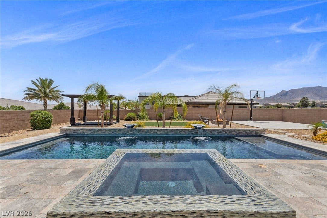 9841 W El Campo Grande Avenue, Las Vegas, NV 89149 An inviting backyard oasis offers a sparkling pool and spa, set against a desert landscape.