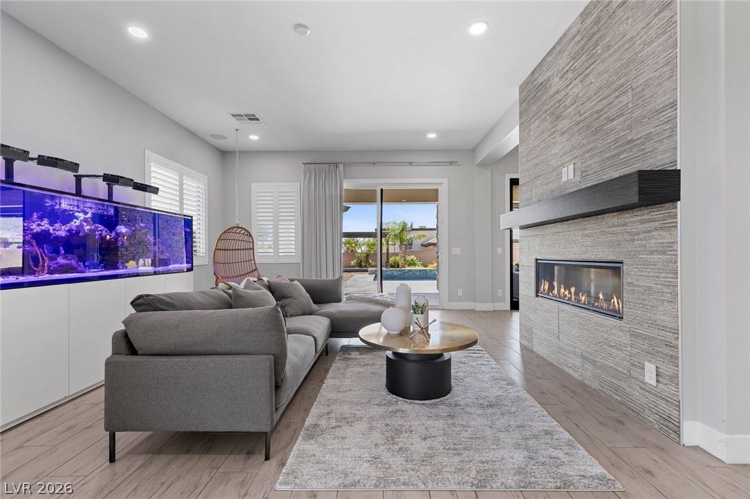 9841 W El Campo Grande Avenue, Las Vegas, NV 89149 A modern fireplace anchors this inviting living space, opening to a private pool and yard.