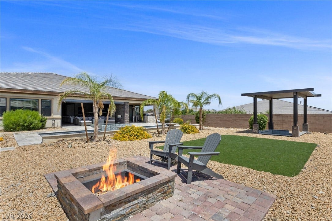 9841 W El Campo Grande Avenue, Las Vegas, NV 89149 An inviting fire pit area anchors this desert landscape, featuring a patio, pool, and pergola for ultimate outdoor leisure.