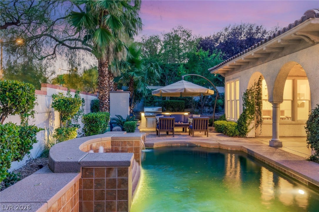 Arched columns and a tile-roofed patio overlook the sparkling backyard pool and spa.