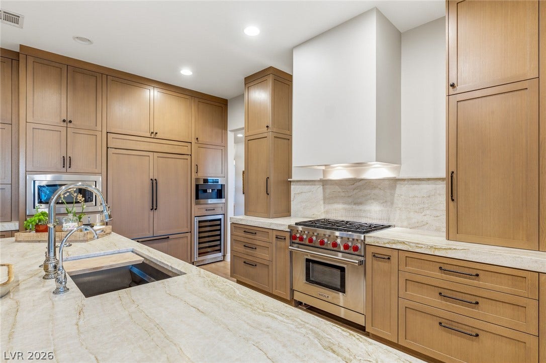 Premium wood cabinetry and stone countertops frame a high-end gas range in this kitchen.