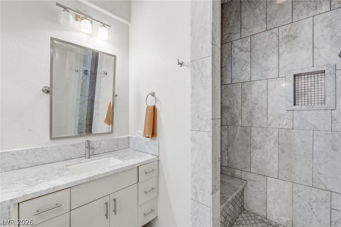 Elegant stone countertops and a matching tiled walk-in shower define this modern bath.