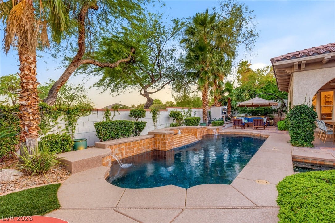 Lush tropical landscaping frames a pristine swimming pool with custom water features.