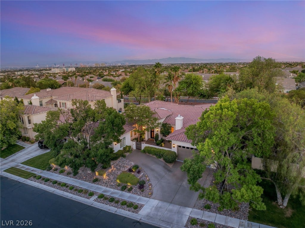 A curved driveway leads past manicured landscaping to this classic tile-roofed residence.