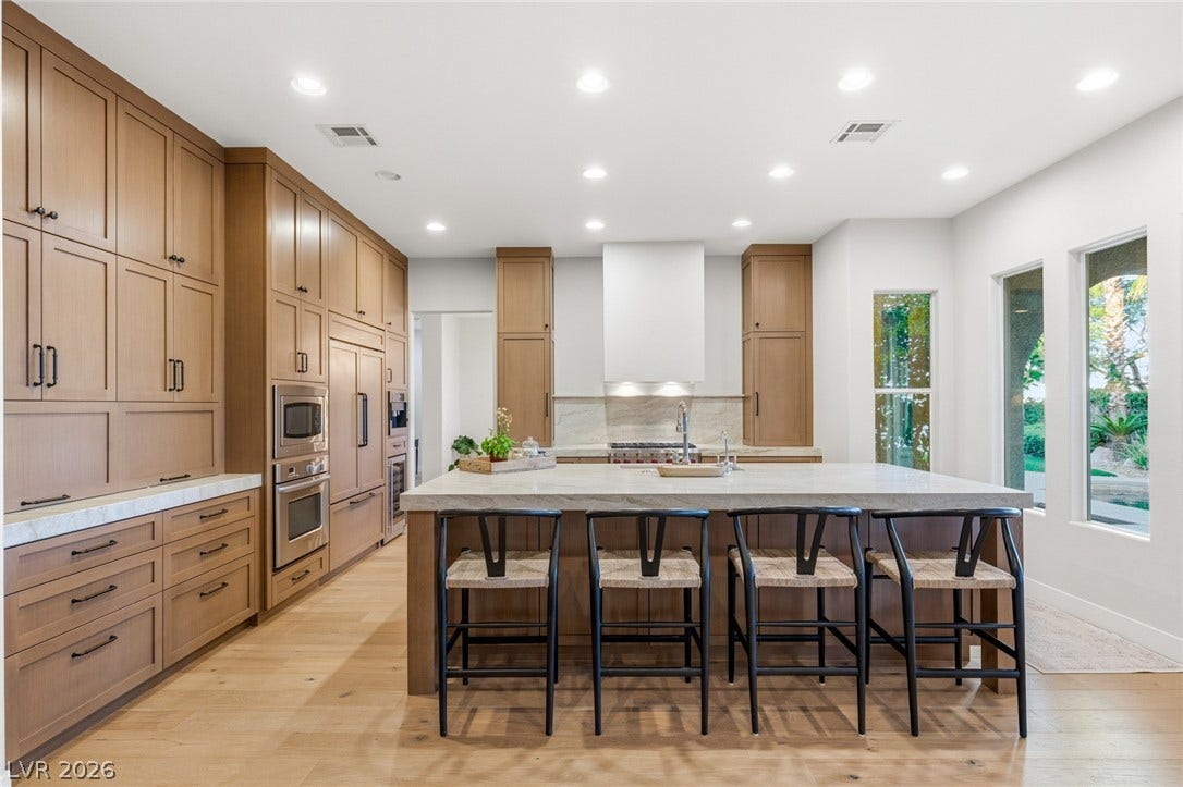 Rich wood cabinetry and a generous central island anchor this light-filled culinary space.